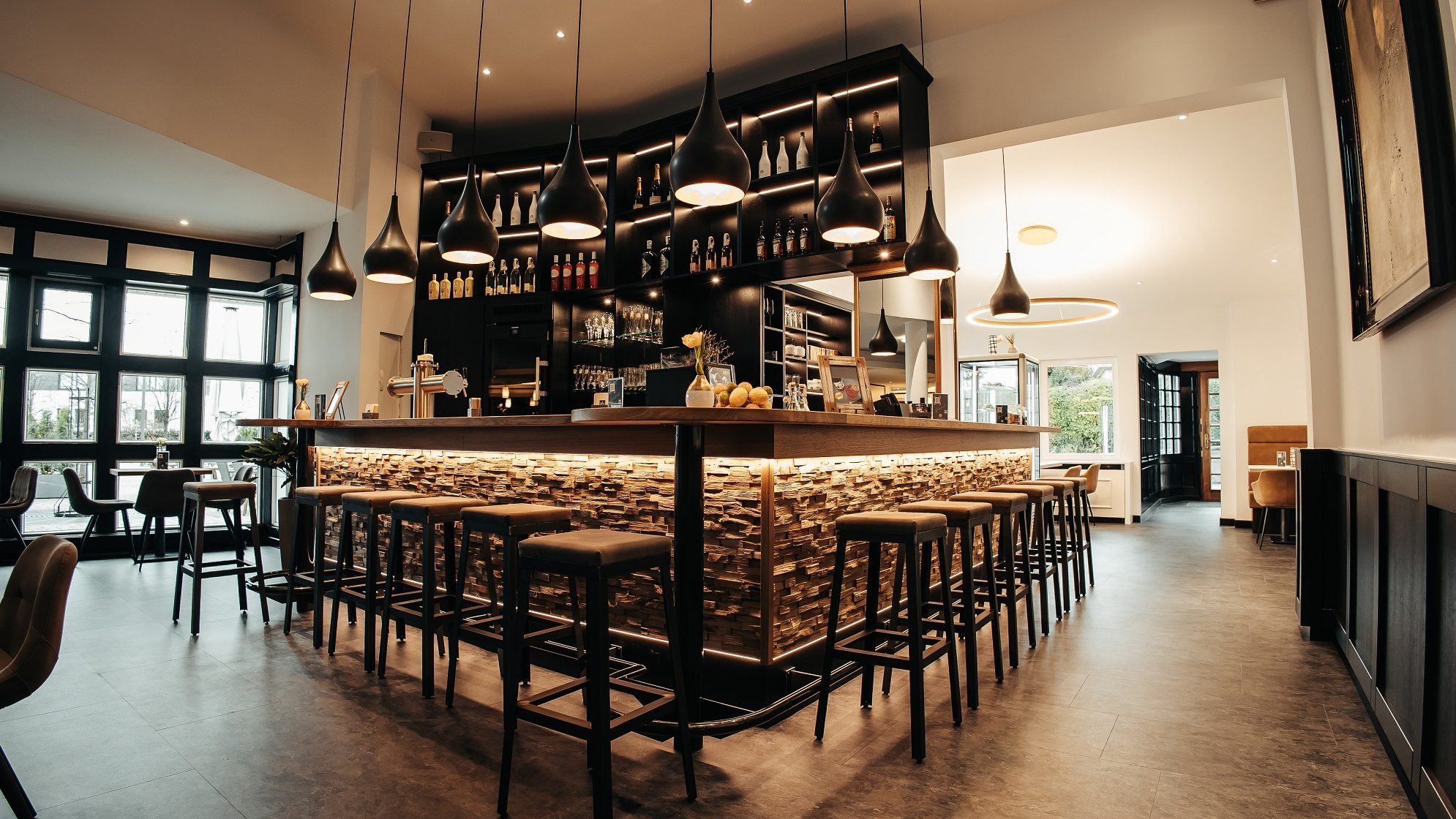 Das Mittendrin Café & Lounge im Parkhotel Nümbrecht, mit stilvoller Bar, hohen Hockern und warmem Licht in einem modernen Ambiente.