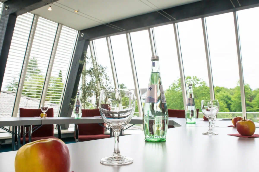 Heller Besprechungsraum mit großen Fenstern, gedecktem Tisch und Blick ins Grüne.