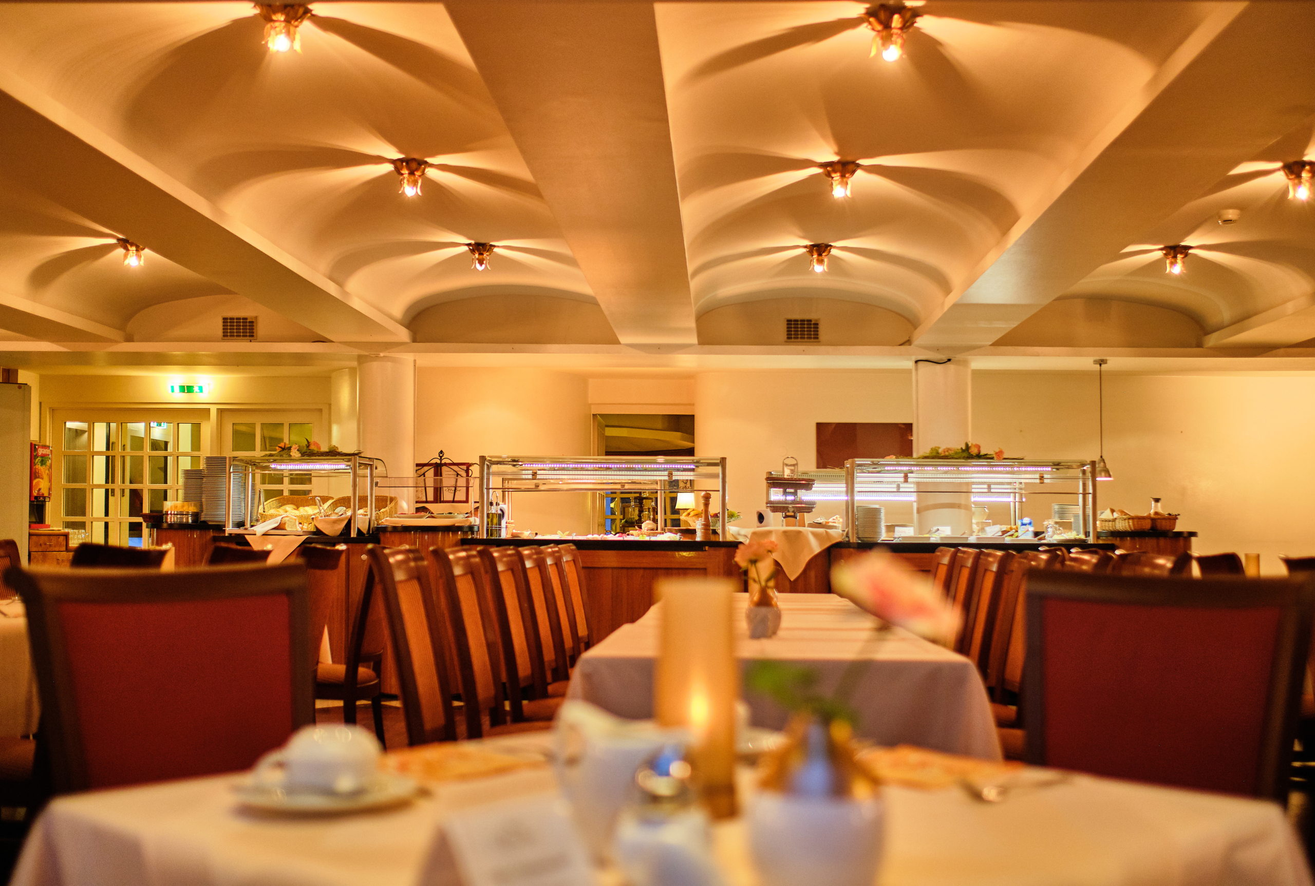 Restaurant oder Bankettsaal mit warmem Licht und gedeckten Tischen.