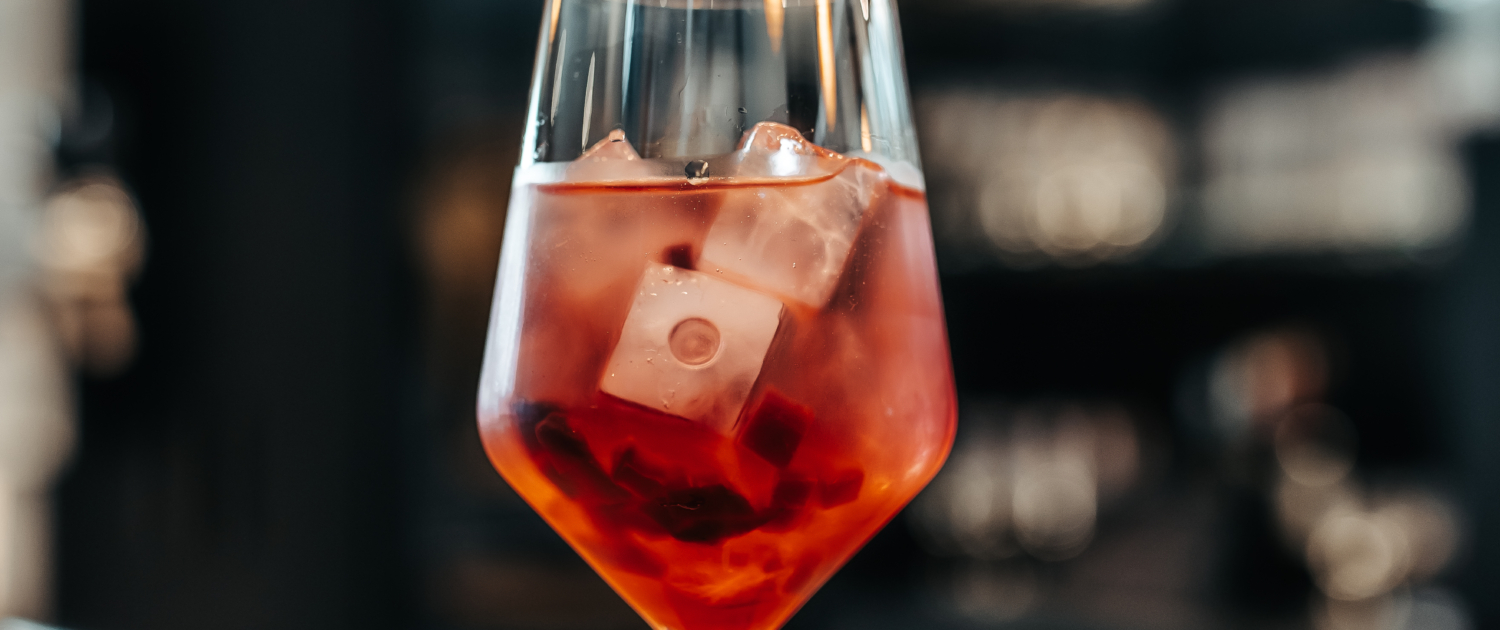 Rotes Getränk in einem Weinglas auf einer Bar oder einem Tisch.